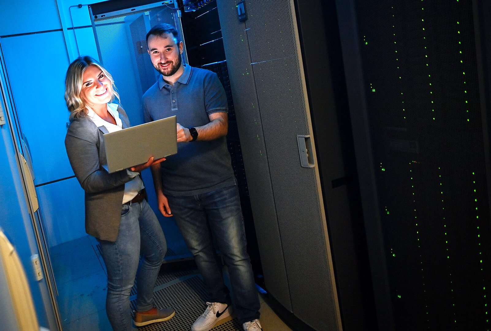 2 Menschen, eine Frau und ein Mann, stehen in einem etwas dunkleren Serverraum
